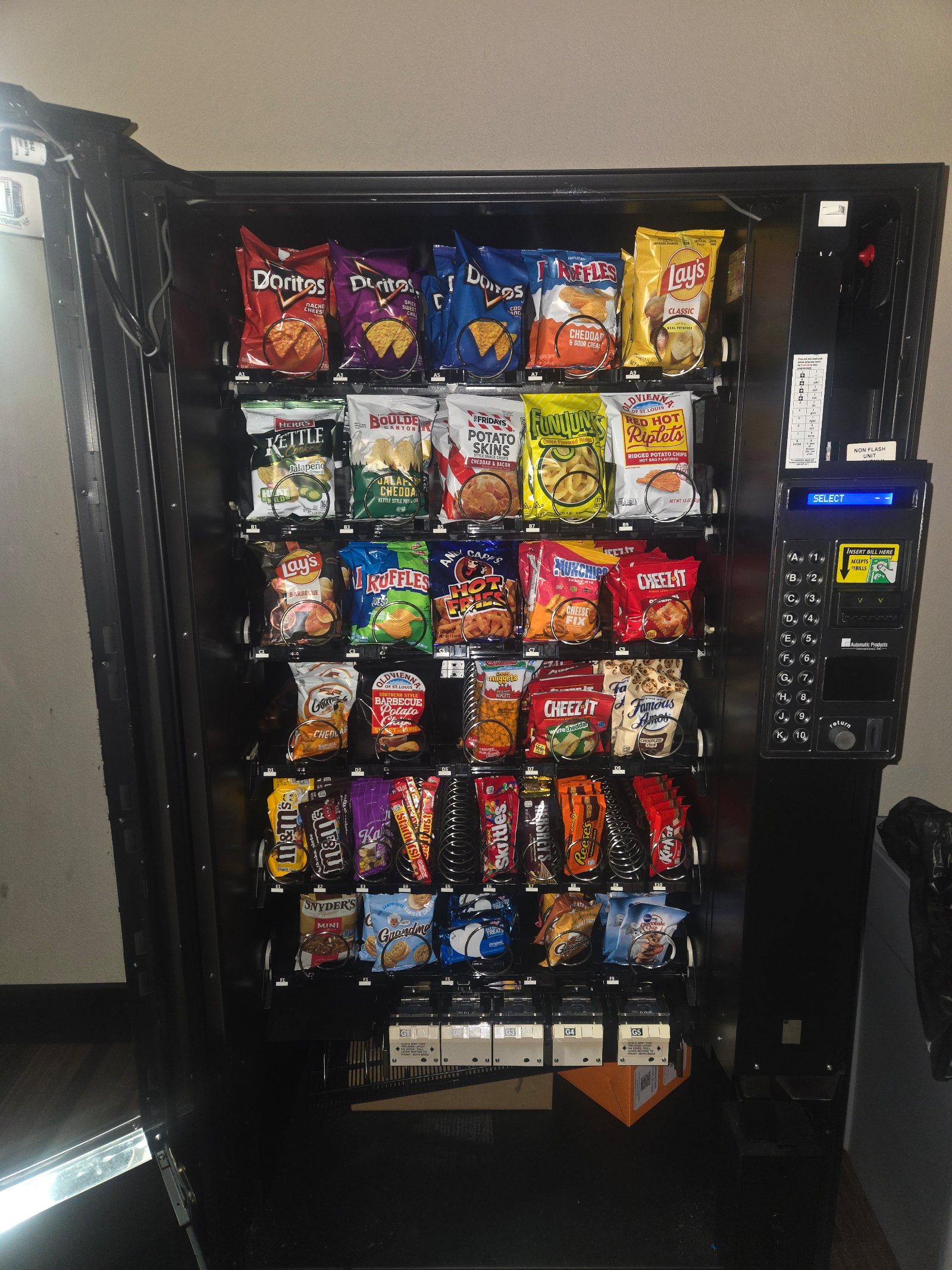 The client's own straight-on photograph of a fully stocked SKS vending machine standing in a real break room: rows full